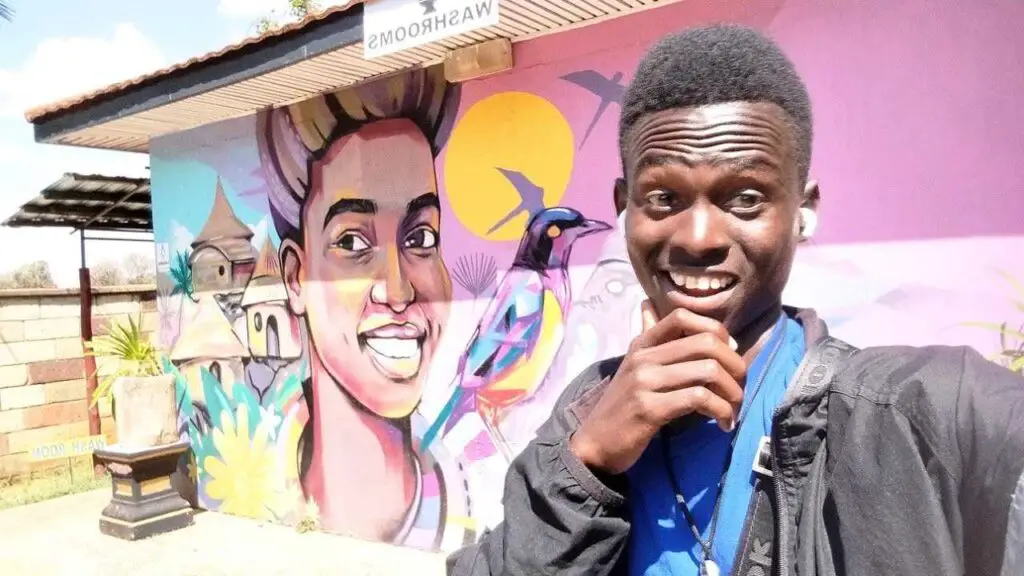 A man taking a selfie in front of a graffiti at Poa Place in Eldoret 