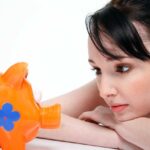 A photo showing a girl looking at piggy bank