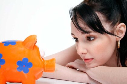 A photo showing a girl looking at piggy bank