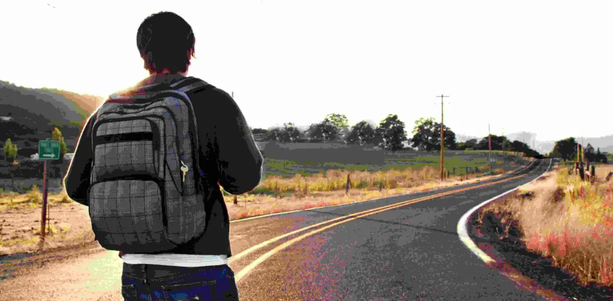 A man carrying a backpack walking along the road alone