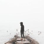 Man watching birds flying over the beach alone - girlfriend wants to travel solo