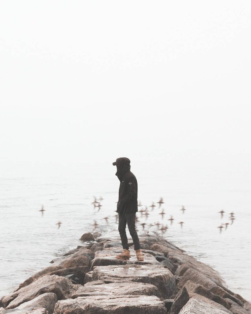 Man watching birds flying over the beach alone - girlfriend wants to travel solo