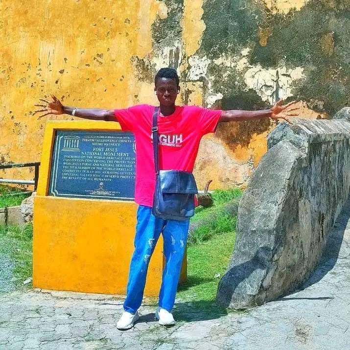 A man standing outside fort jesus opening his arms 