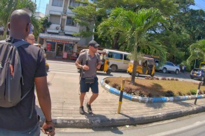 A tourist crossing a road along Moi Avenue close to tusk monuments in Mombasa