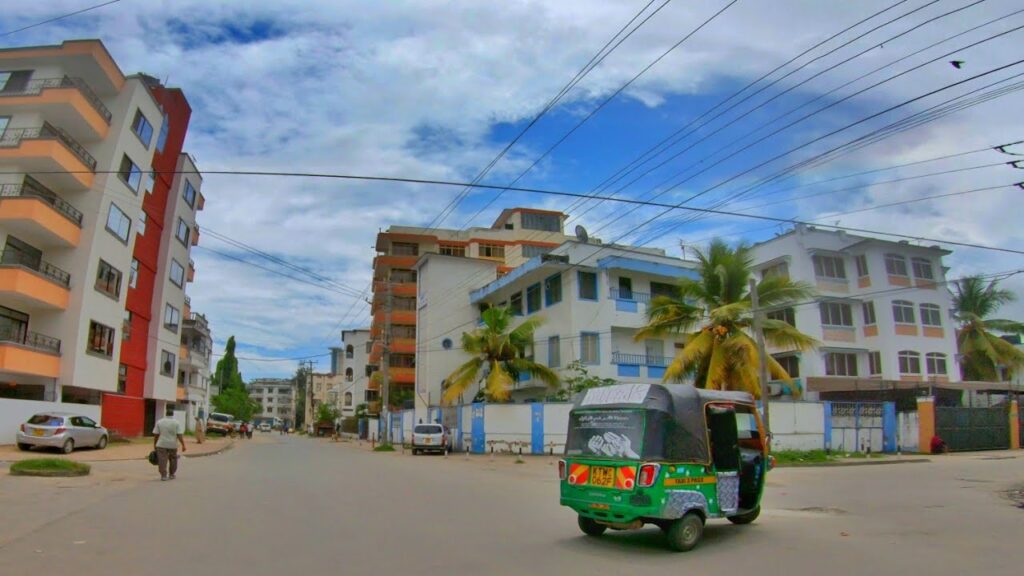 Hot day in Mombasa, clear skies, buildings, palm trees and a tuktuk 