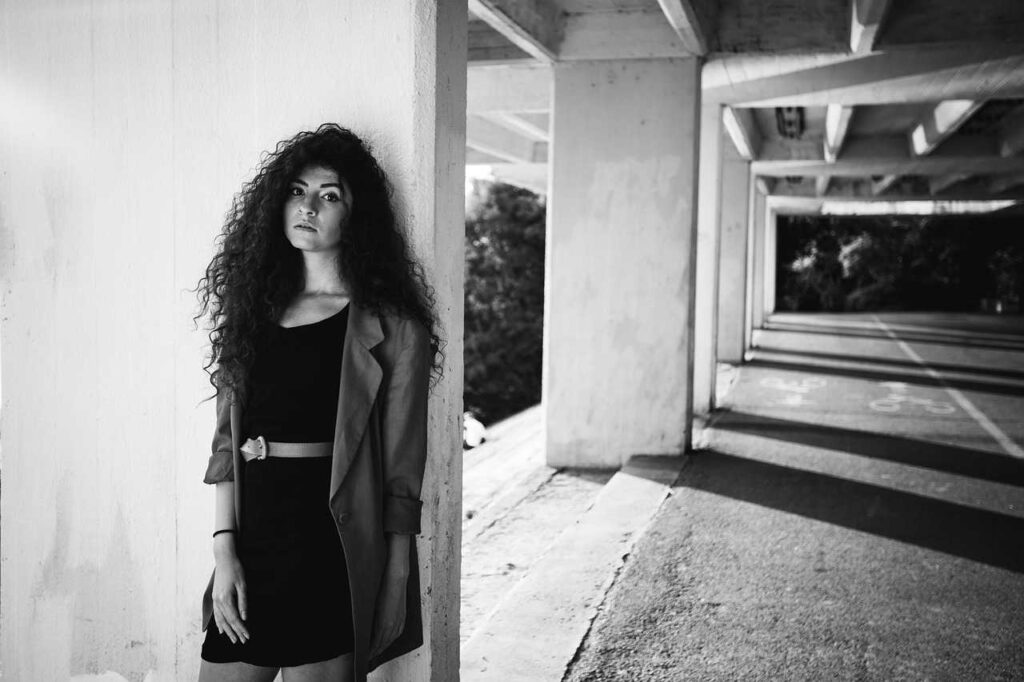 A woman with long hair standing while leaning on the wall with her back 