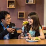 A man drinking while a woman eating in a house