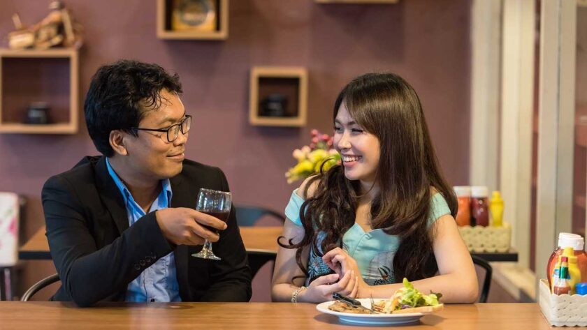 A man drinking while a woman eating in a house