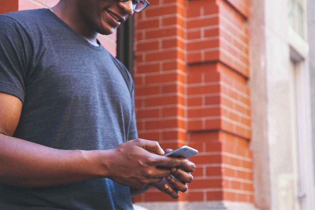 A man reading a text while smiling 