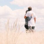 A man and a woman holding each other in open field alone