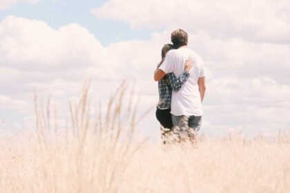 A man and a woman holding each other in open field alone