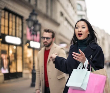 a woman holding hand her boyfriend while carrying shopping bags