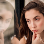 a woman leaning on a window pane while thinking