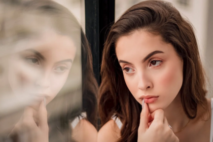 a woman leaning on a window pane while thinking