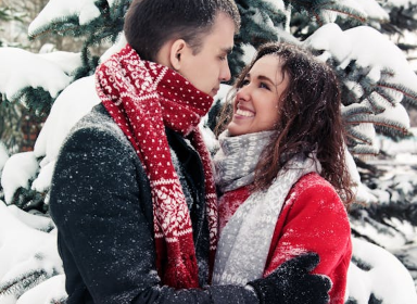 a man and a woman holding each other while it snows